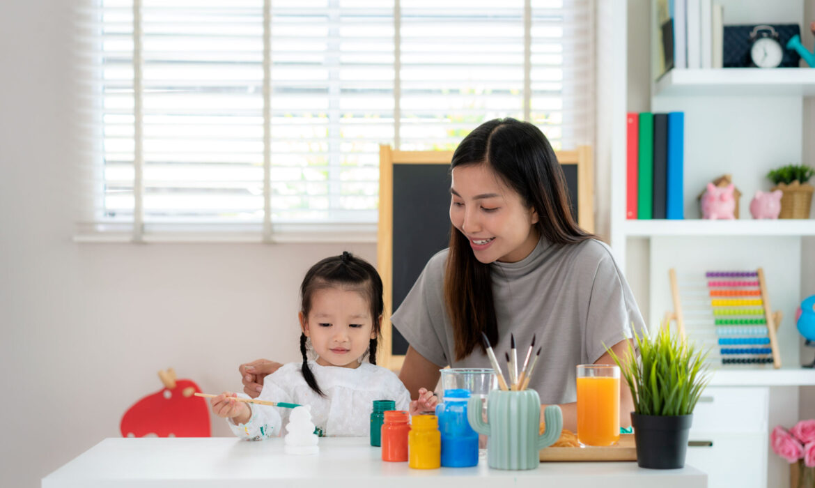 Mother conducting a home-based ABA therapy session with her daughter, using colorful paints and art activities to support autism development in a Singapore home setting.