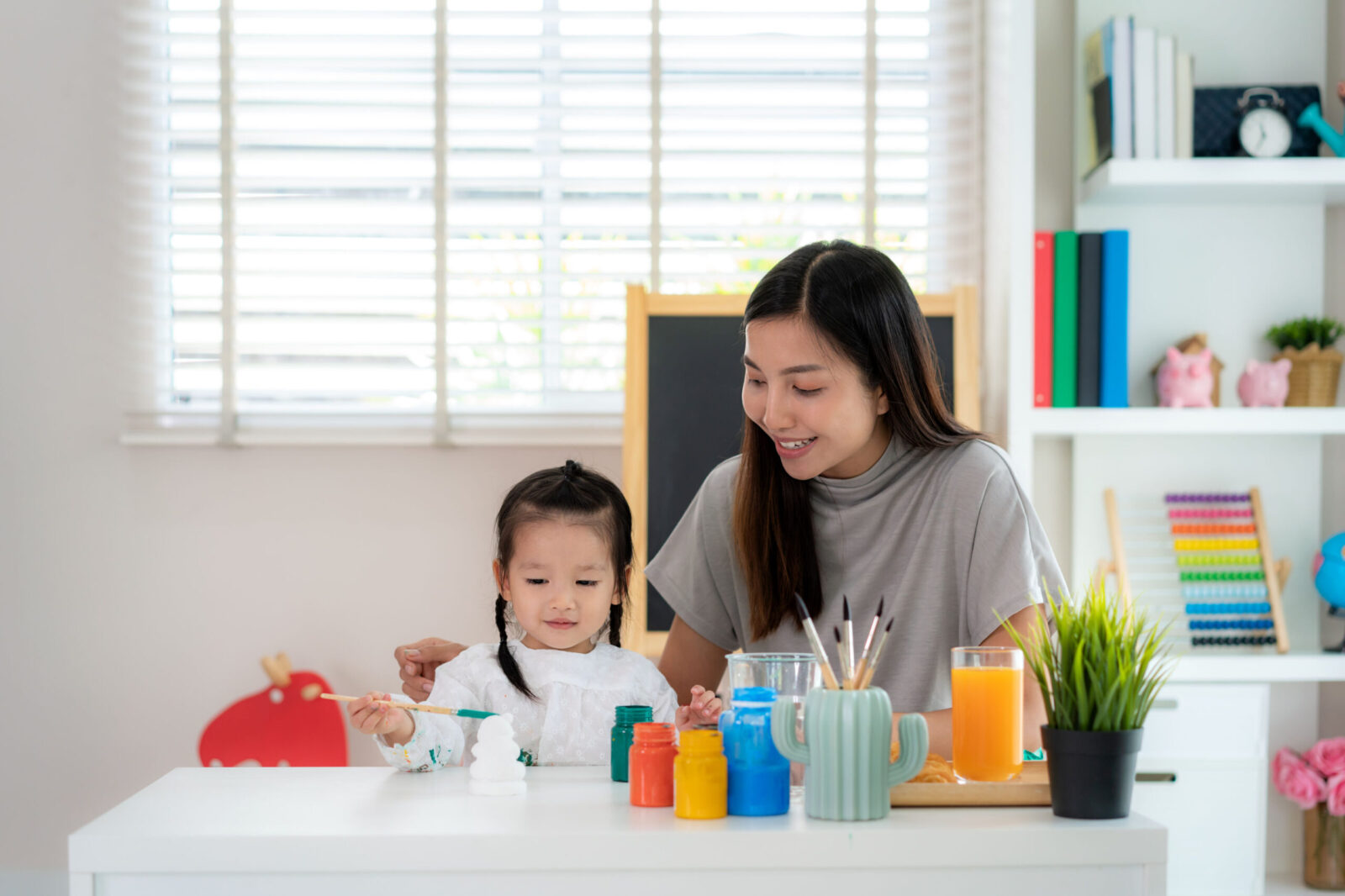 Mother conducting a home-based ABA therapy session with her daughter, using colorful paints and art activities to support autism development in a Singapore home setting.