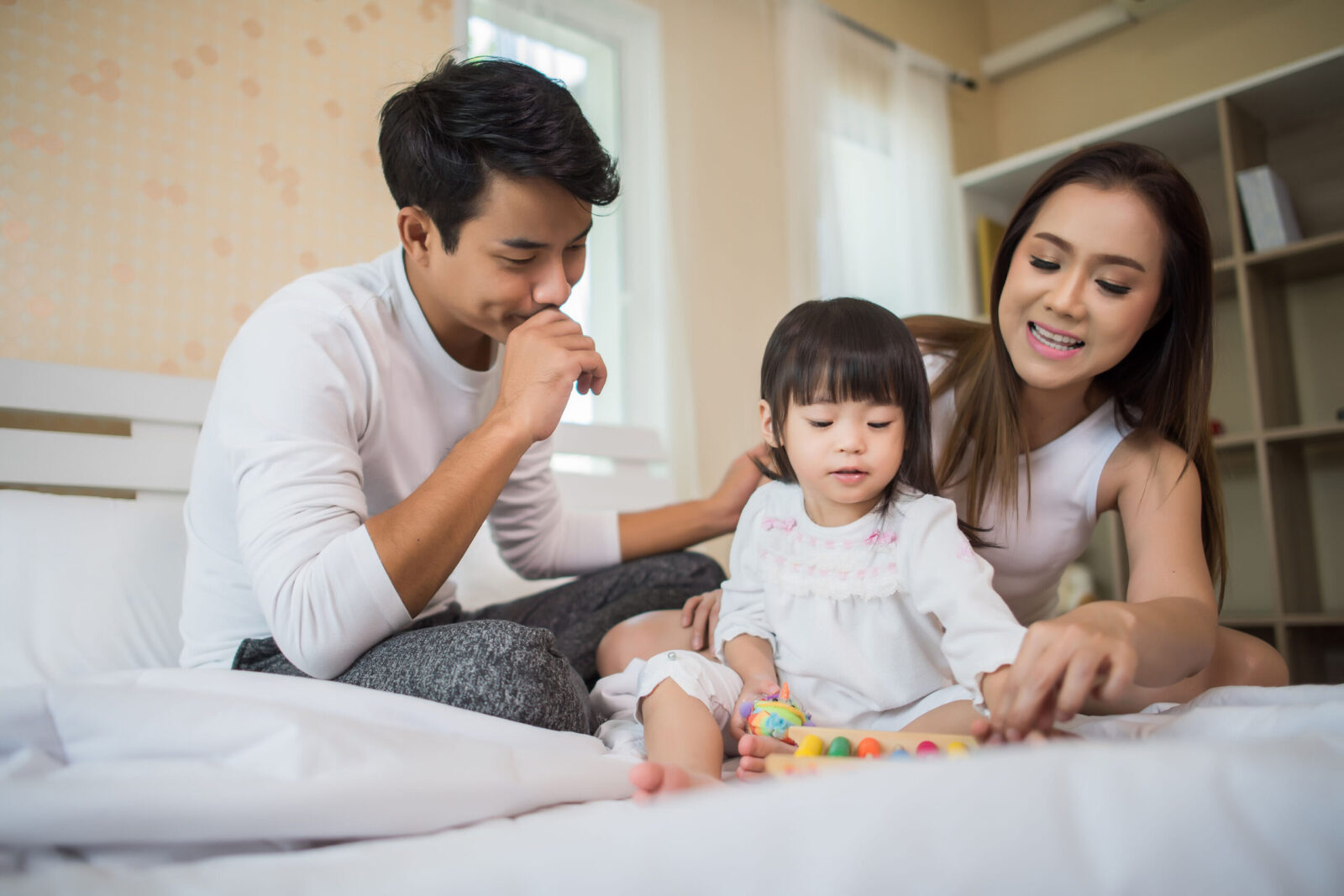 Parents engaging in a home ABA therapy activity with their young daughter, using toys to support early autism intervention and family involvement in Singapore.