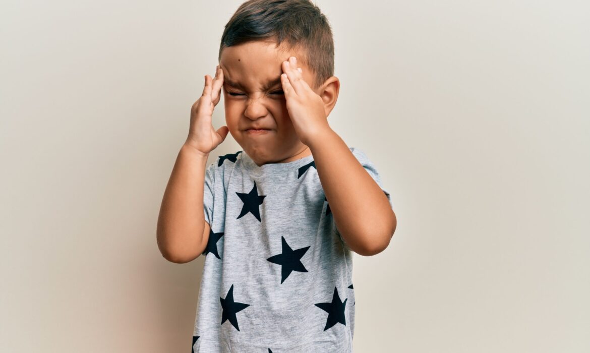 Frustrated young boy with closed eyes and hands on head, expressing distress—illustrating emotional overwhelm and meltdowns in autistic children, relevant to parenting strategies and autism support.