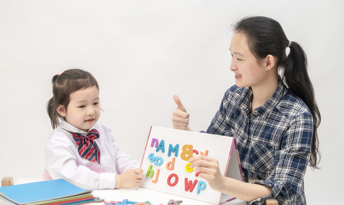 Therapist teaching young child with autism using colorful alphabet letters during home-based therapy session in Singapore