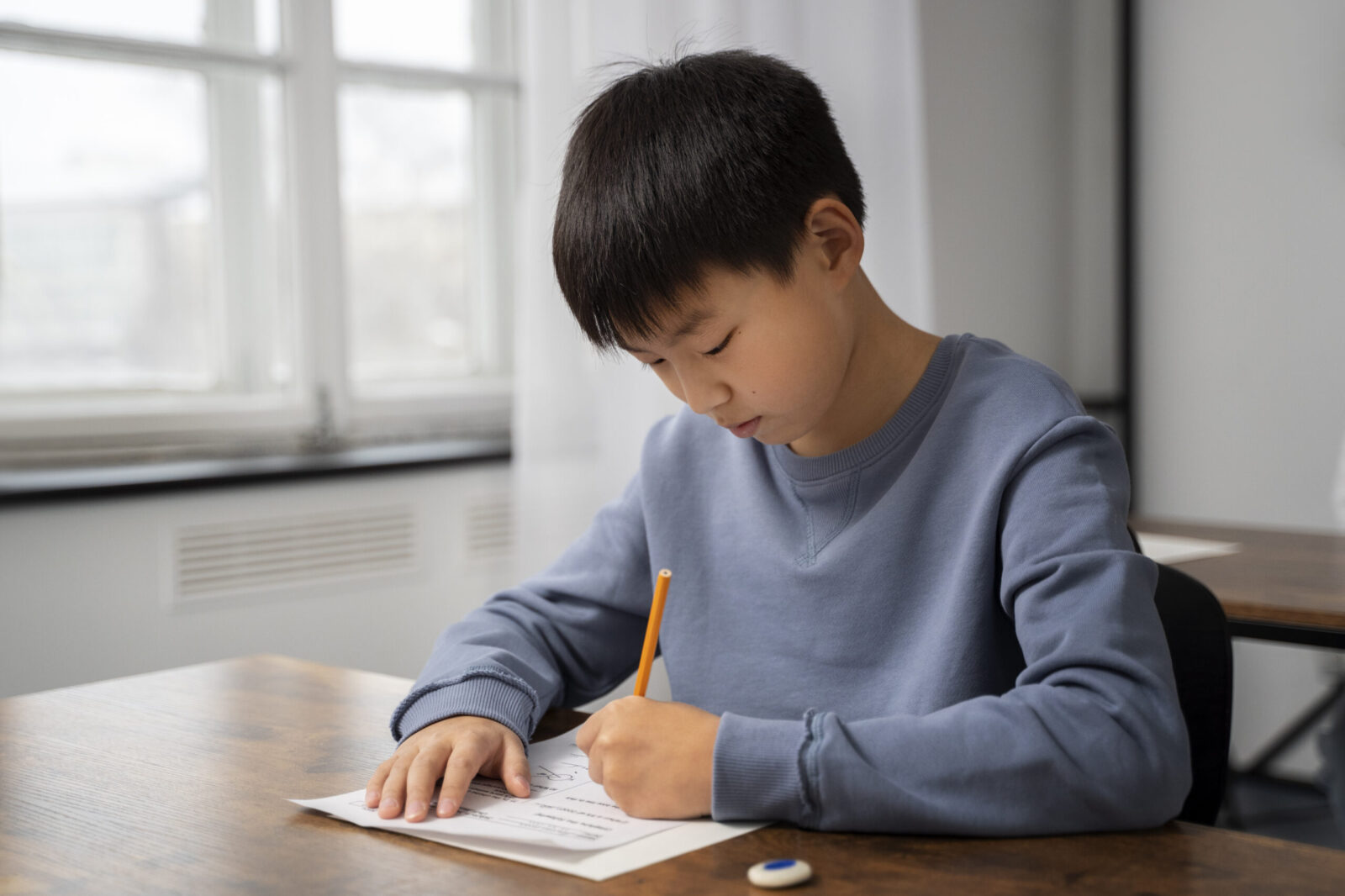 Focused young boy completing a written test at a desk in a classroom, representing the role of psychological assessments in unlocking children's cognitive and academic potential.