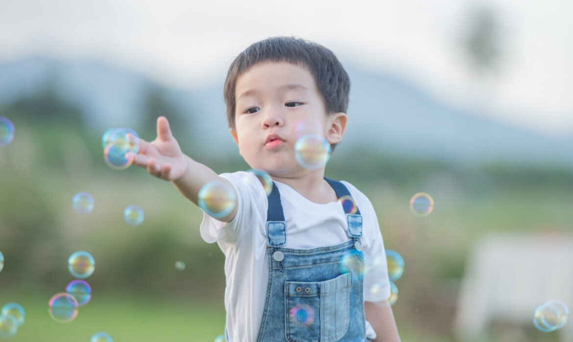 Child engaging in playful bubble activity outdoors, illustrating integrating therapeutic strategies into everyday activities for children with autism.