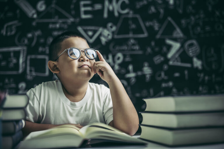Boys with glasses write books and think in the classroom