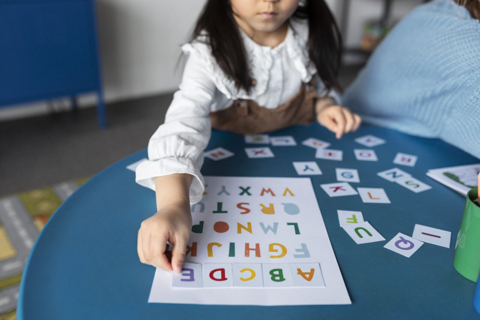 Child engaging in a learning activity with colorful alphabet cards, illustrating early intervention for global developmental delay (GDD).