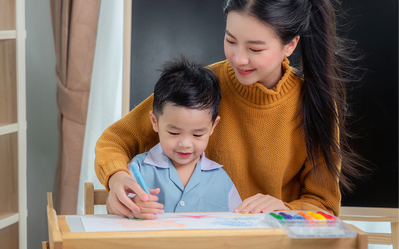 Teacher supporting a child with autism in a learning environment.