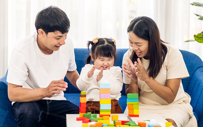 Parents supporting a child during autism therapy session.