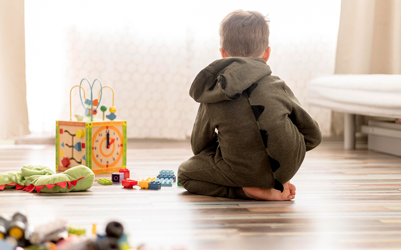 Child playing alone with toys, showing subtle signs of autism.
