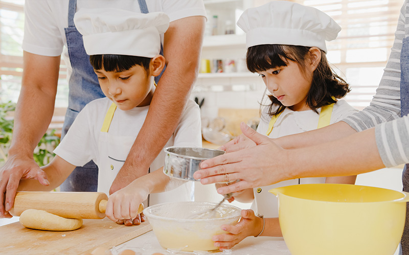 Children attending a cooking class, wearing an apron and a hat