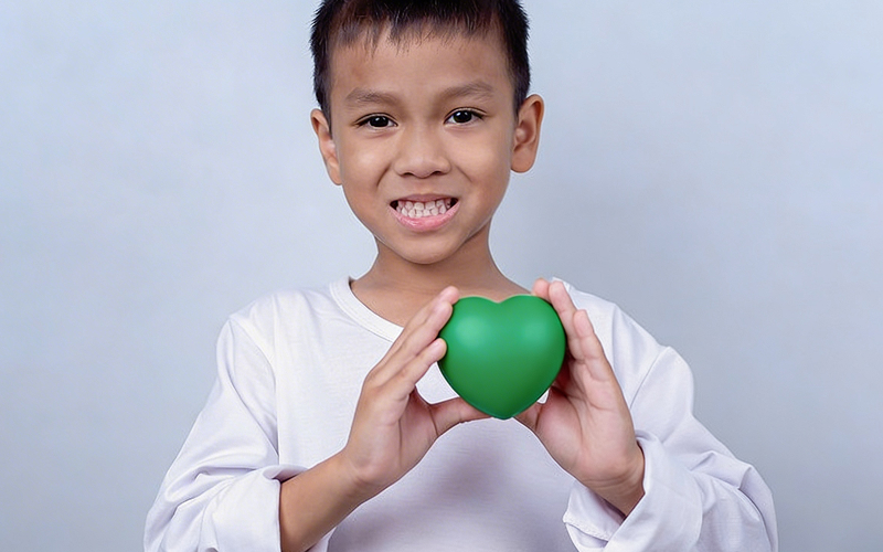 Smiling young boy holding heart representing autism support.
