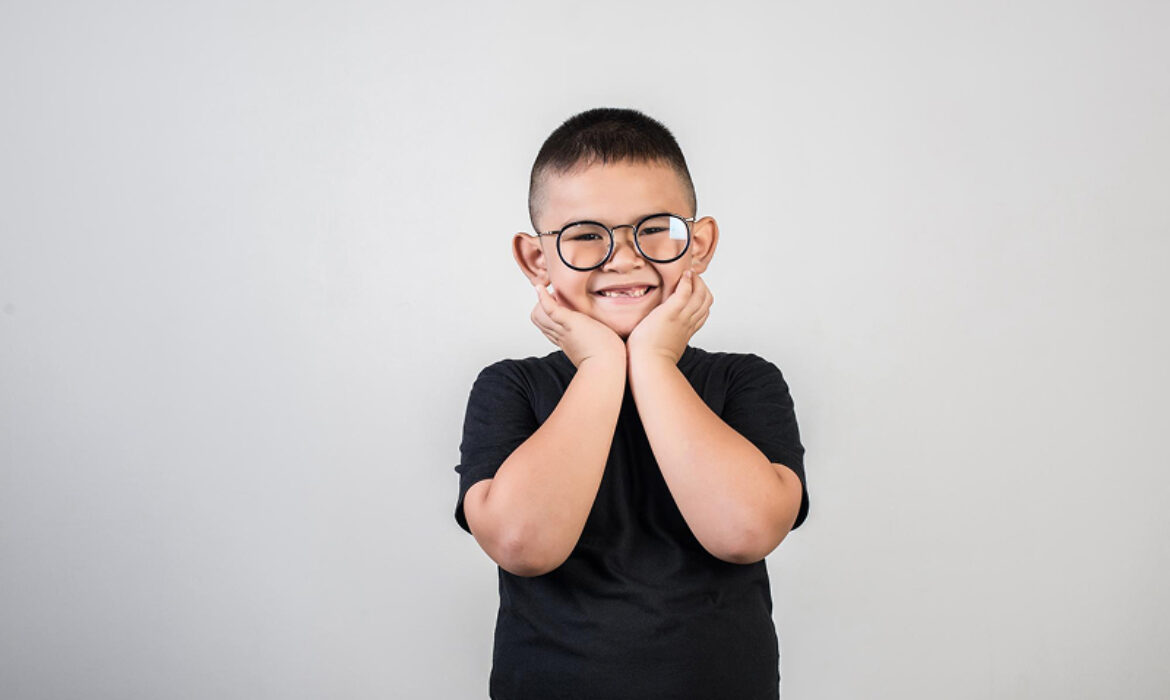 Young boy with glasses smiling during a therapy session.
