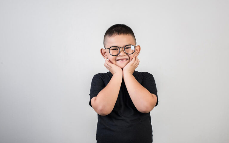 Young boy with glasses smiling during a therapy session.